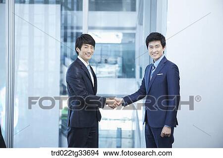 Picture - Businessmen shaking hands together. Fotosearch