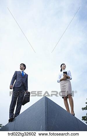 Stock Image - Businessmen standing with briefcase and planner. Fotosearch