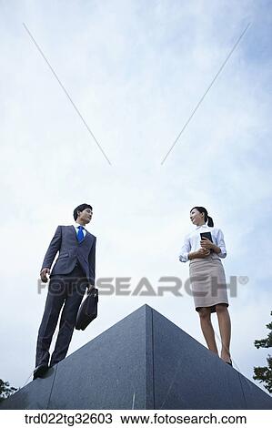 Stock Image - Businessmen standing with briefcase and planner. Fotosearch