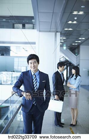 Stock Photo - Businessmen taking a break in the hallway. Fotosearch