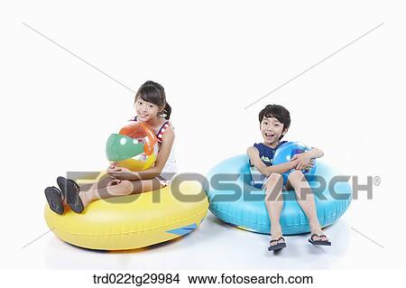 Picture - children holding beach balls and sitting on the tubes. Fotosearch