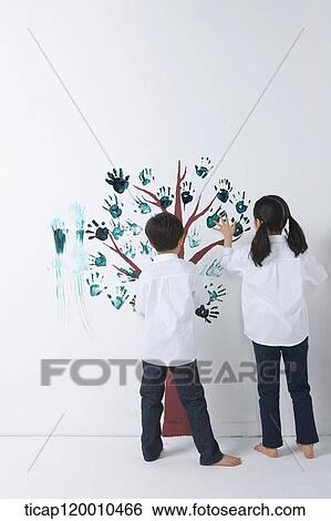 Stock Photograph - Children painting the tree with hands. Fotosearch