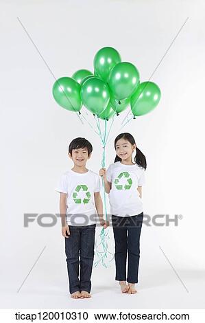 Stock Image - Children wearing recycling shirt with green balloons. Fotosearch