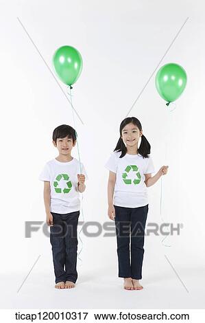 Stock Photo - Children wearing recycling shirt with green balloons. Fotosearch