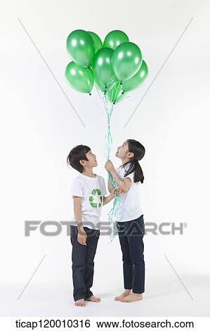 Stock Photograph - Children wearing recycling shirt with green balloons. Fotosearch