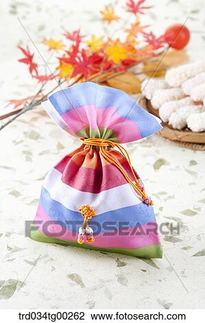 Stock Image - Colorful lucky bag with colored leaves and Korean dessert behind. Fotosearch