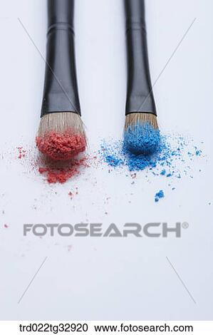 Stock Image - Cosmetic brushes with red and blue powder. Fotosearch