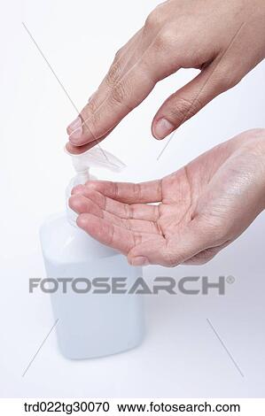 Stock Image - finger pushes pump of liquid soap. Fotosearch