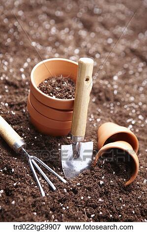 Stock Photo - flowerpots and shovel and hook is on the dirt. Fotosearch