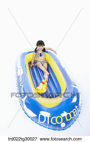 Stock Photo - girl is sitting on boat with dolls. Fotosearch