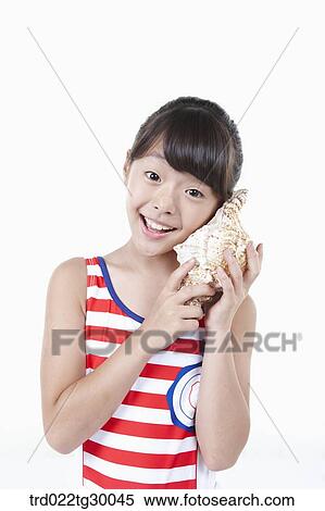 girl put the turban shell to her ear View Large Photo Image Stock Photography - girl put the turban shell to her ear. Fotosearch