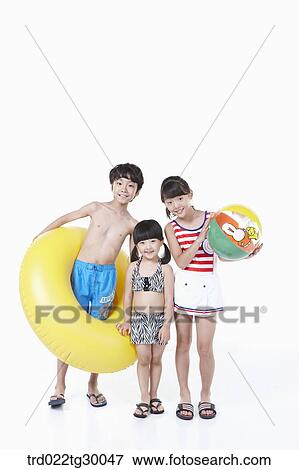 Stock Photo - girls and boy are in swimsuit with tube and beach ball. Fotosearch