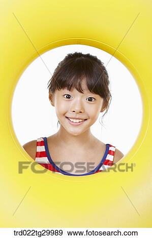 Stock Photo - girl's face was seen through the hole of tube. Fotosearch