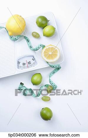 Stock Photograph - Lemon, lime, and measuring tape on the scale. Fotosearch