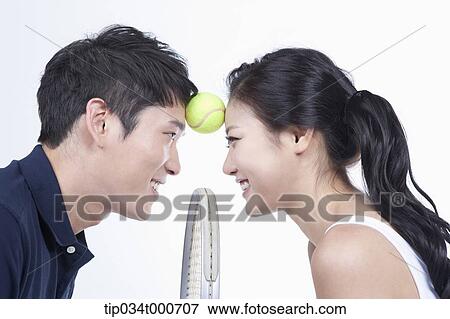 Stock Photo - Male and female tennis players between a ball. Fotosearch