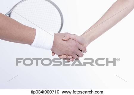 Stock Image - Male and female tennis players shaking hands. Fotosearch