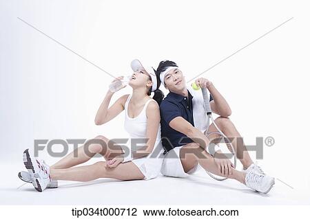 Stock Image - Male and female tennis players taking a break. Fotosearch