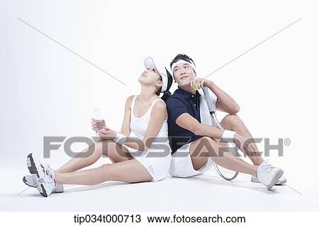 Stock Image - Male and female tennis players taking a break. Fotosearch