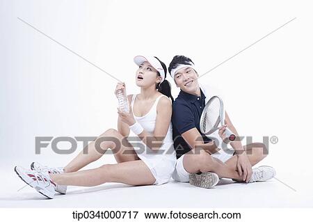 Stock Photo - Male and female tennis players taking a break. Fotosearch