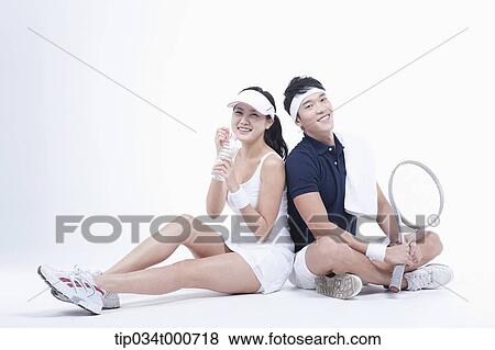 Stock Photo - Male and female tennis players taking a break. Fotosearch