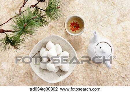 Stock Image - Rice cake and tea setting with pine branch around. Fotosearch