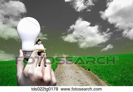 Stock Photo - woman is sitting on someone's hand which was holding light bulb. Fotosearch
