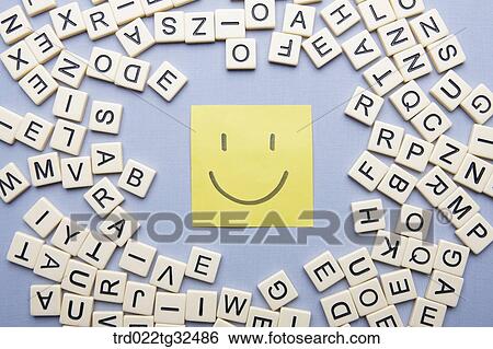 Stock Photograph - Yellow smiling note with alphabet blocks around. Fotosearch