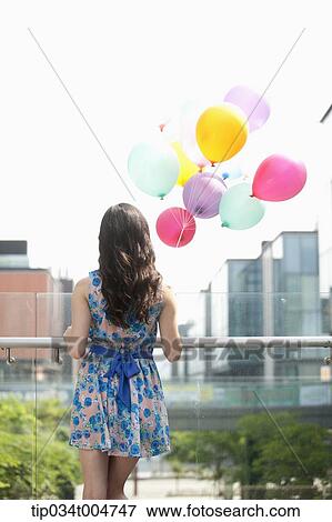 Stock Photo - a back shot of a woman with a bunch of balloons. Fotosearch