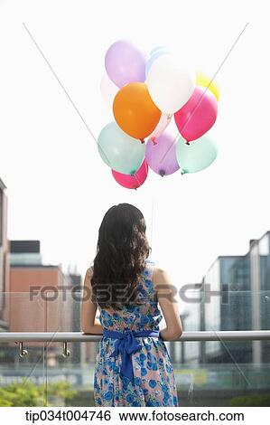 Stock Photograph - a back shot of a woman with a bunch of balloons. Fotosearch