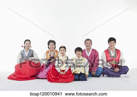 Stock Image - a big family sitting on the floor wearing Hanbok. Fotosearch