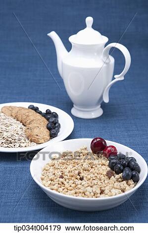 Stock Photo - a bowl of cereal, a plate of cookies and berries and a milk pot. Fotosearch