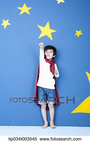 a boy posing like a superman with a red cape around his neck in blue background with stars View Large Photo Image Stock Photography - a boy posing like a superman with a red cape around his neck in blue background with stars. Fotosearch