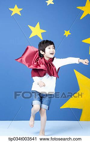 Stock Image - a boy posing like a superman with fluttering red cape. Fotosearch