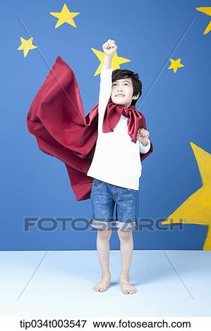 Stock Photo - a boy posing like a superman with fluttering red cape. Fotosearch