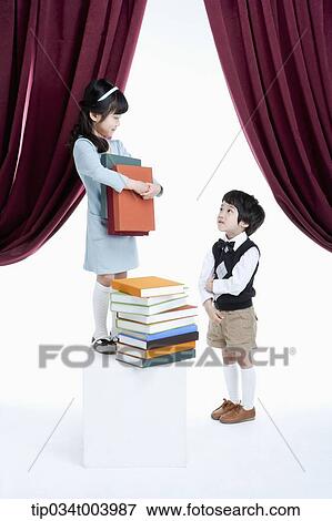 Stock Photo - a boy standing next to a girl with pile of books on a stage. Fotosearch