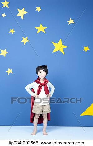 a boy wearing a red cape posing like a superman in front of a blue wall full of stars View Large Photo Image Stock Photograph - a boy wearing a red cape posing like a superman in front of a blue wall full of stars. Fotosearch