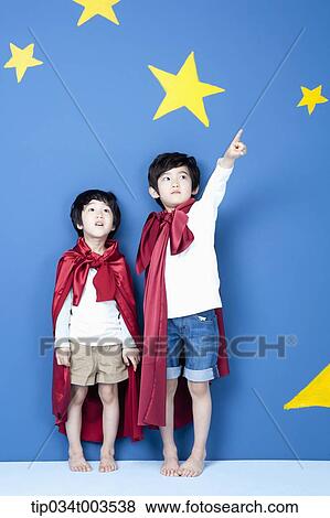 Stock Photo - a boy wearing a superman cape pointing . Fotosearch