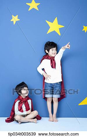 a boy wearing a superman cape pointing at a place while younger brother sat on the floor View Large Photo Image Stock Photo - a boy wearing a superman cape pointing at a place while younger brother sat on the floor. Fotosearch