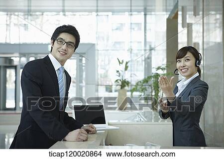 Picture - a businessman and help desk woman smiling at camera . Fotosearch