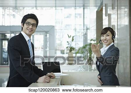 Stock Image - a businessman and help desk woman smiling at camera . Fotosearch