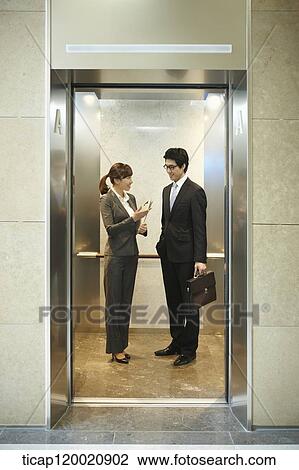 Stock Image - a businessman and woman discussing in elevator. Fotosearch