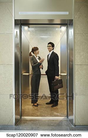 Stock Photo - a businessman and woman discussing in elevator. Fotosearch