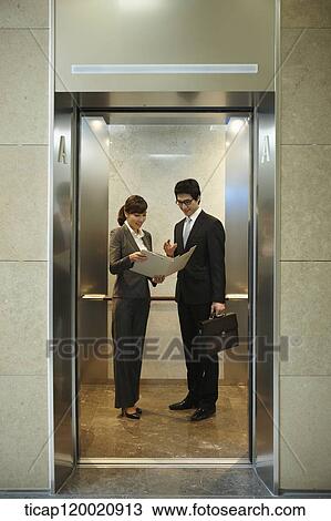 a businessman and woman discussing with documents in elevator View Large Photo Image Stock Image - a businessman and woman discussing with documents in elevator. Fotosearch