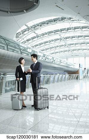 Stock Image - a businessman and woman discussing with document in Incheon airport. Fotosearch