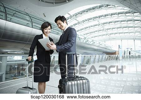 Stock Photo - a businessman and woman discussing with document in Incheon airport. Fotosearch