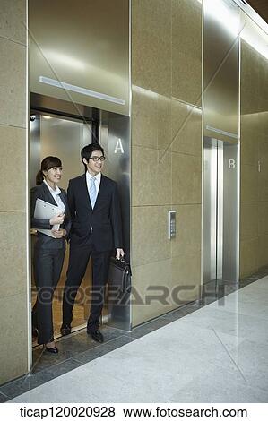 a businessman and woman getting of an elevator View Large Photo Image Stock Photo - a businessman and woman getting of an elevator. Fotosearch