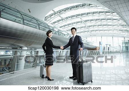 Stock Photo - a businessman and woman shaking hands in Incheon airport. Fotosearch