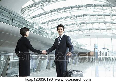 Stock Photograph - a businessman and woman shaking hands in Incheon airport. Fotosearch