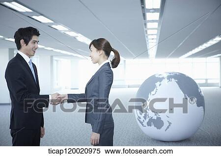 a businessman and woman shaking hands next to a huge globe in an empty room View Large Photo Image Stock Photography - a businessman and woman shaking hands next to a huge globe in an empty room. Fotosearch