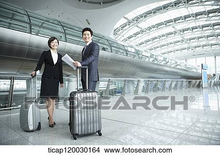 Picture - a businessman and woman smiling at camera in Incheon airport. Fotosearch